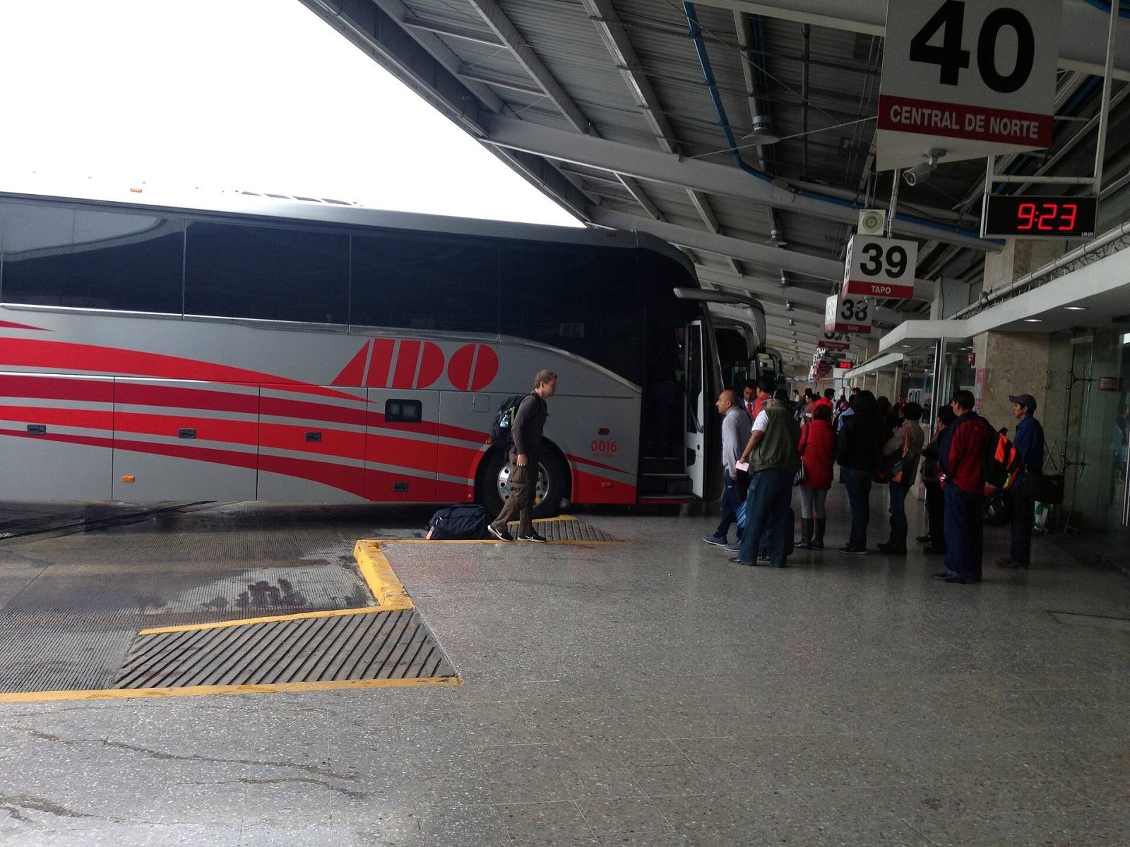 A red and white ADO coach at a platform of the CAPU bus station in Puebla