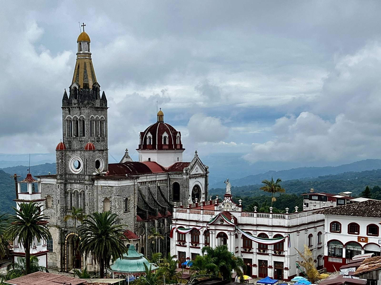 The tall clock tower of Cuetzalan’s parish church above the town, with green hills behind