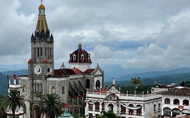 The tall clock tower of Cuetzalan’s parish church above the town, with green hills behind