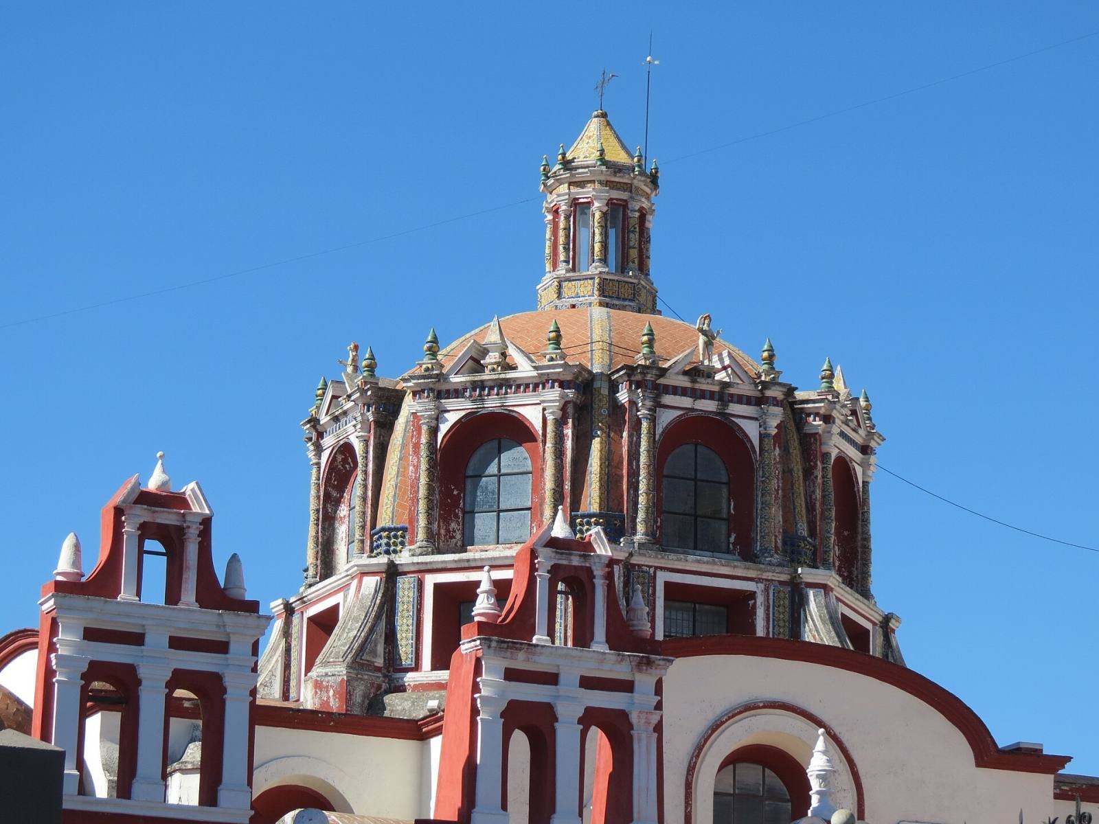 The red and white tiled dome of the Rosary Chapel against a clear blue sky
