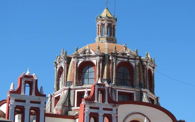 The red and white tiled dome of the Rosary Chapel against a clear blue sky