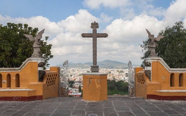 A stone cross in the atrium of the church on top of the Cholula pyramid, with the town spread out below
