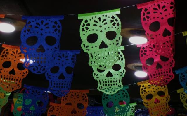 Colourful papel picado banners cut with skull designs, hanging in rows