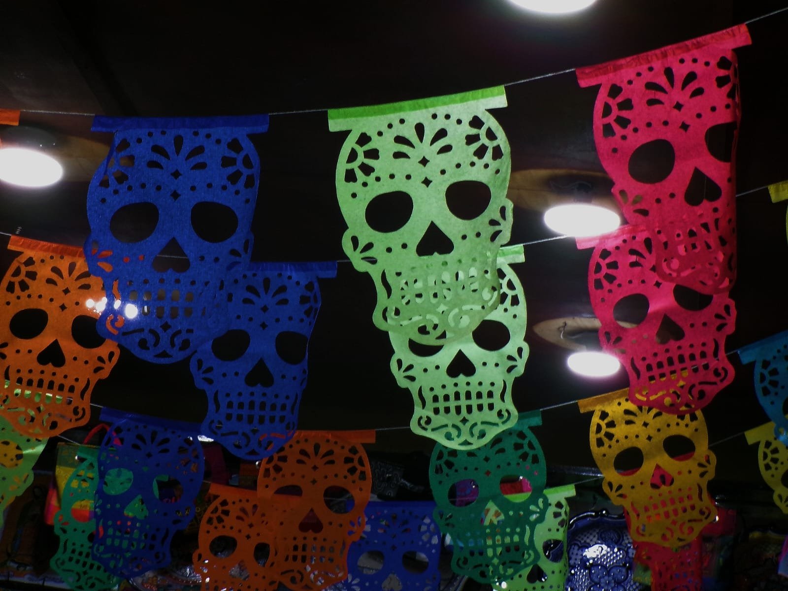 Colourful papel picado banners cut with skull designs, hanging in rows