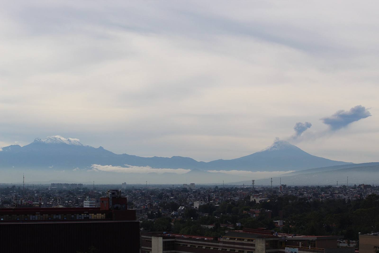 Popocatépetl and Iztaccíhuatl rising above the haze of the valley at dawn