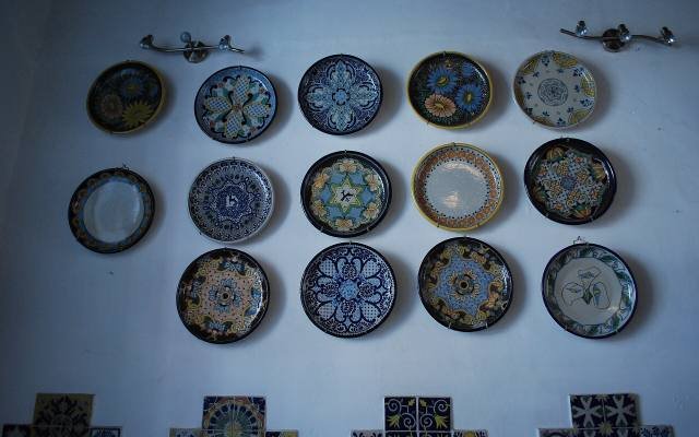 Hand-painted Talavera plates in blue, yellow and green hanging on a white wall