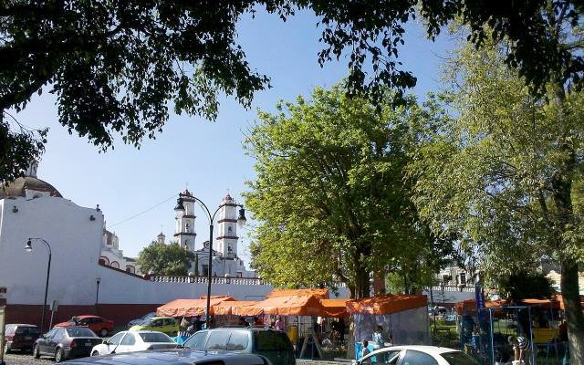 Trees and the church towers of the Barrio de Analco under a blue sky