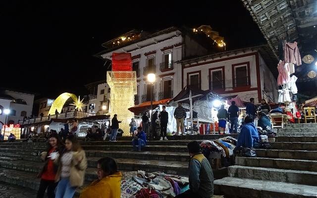 People on the steps of Cuetzalan’s main square at night, among lit stalls